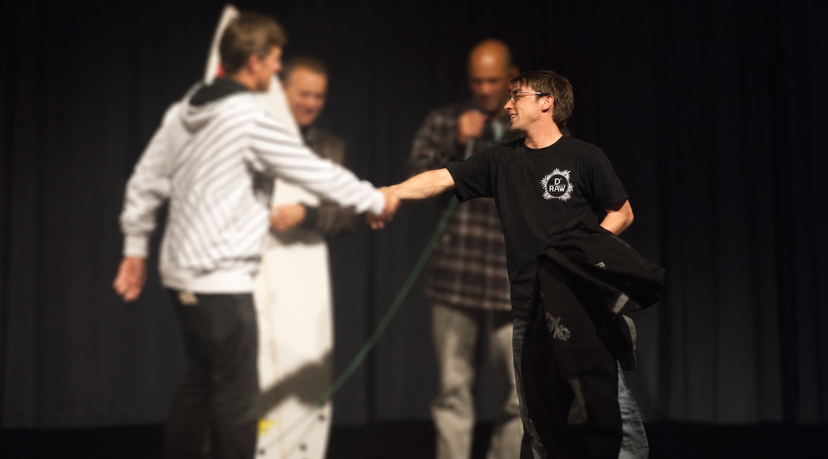 Marcello wearing a black D’Raw shirt, with the other people softly blurred