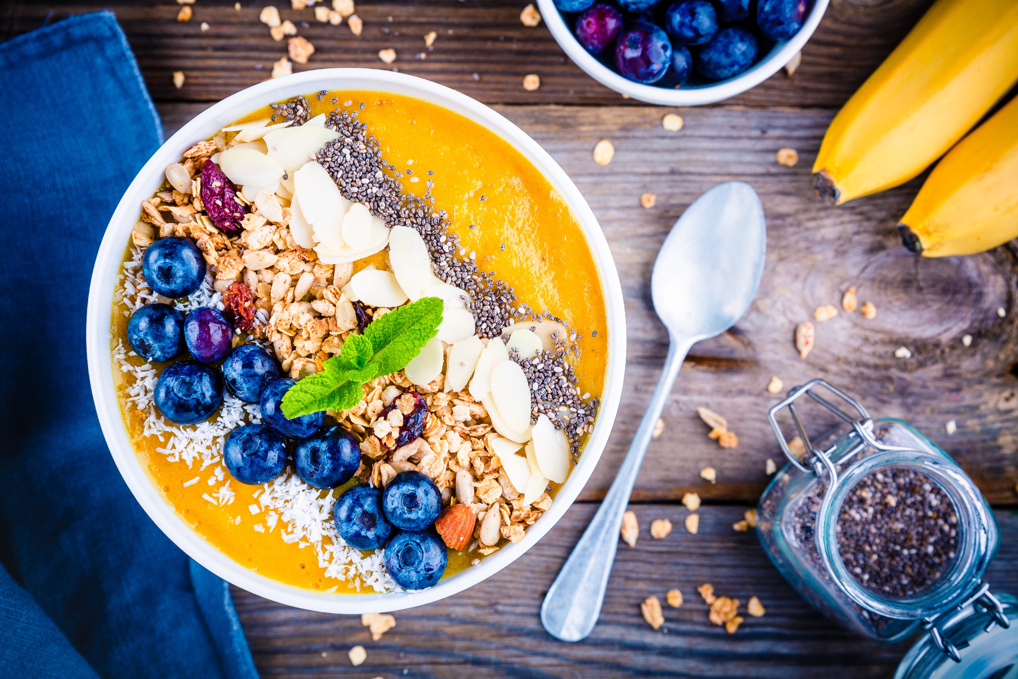 Mango smoothie bowl topped with blueberries, granola, coconut and seeds