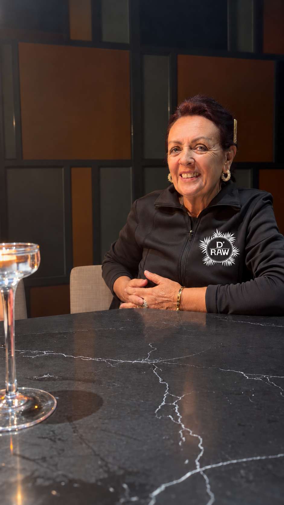 Sônia wearing a black shirt with a monochrome D’Raw logo